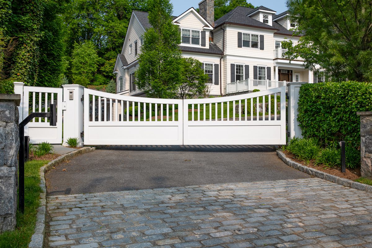 Modern white composite gate on a hilly driveway