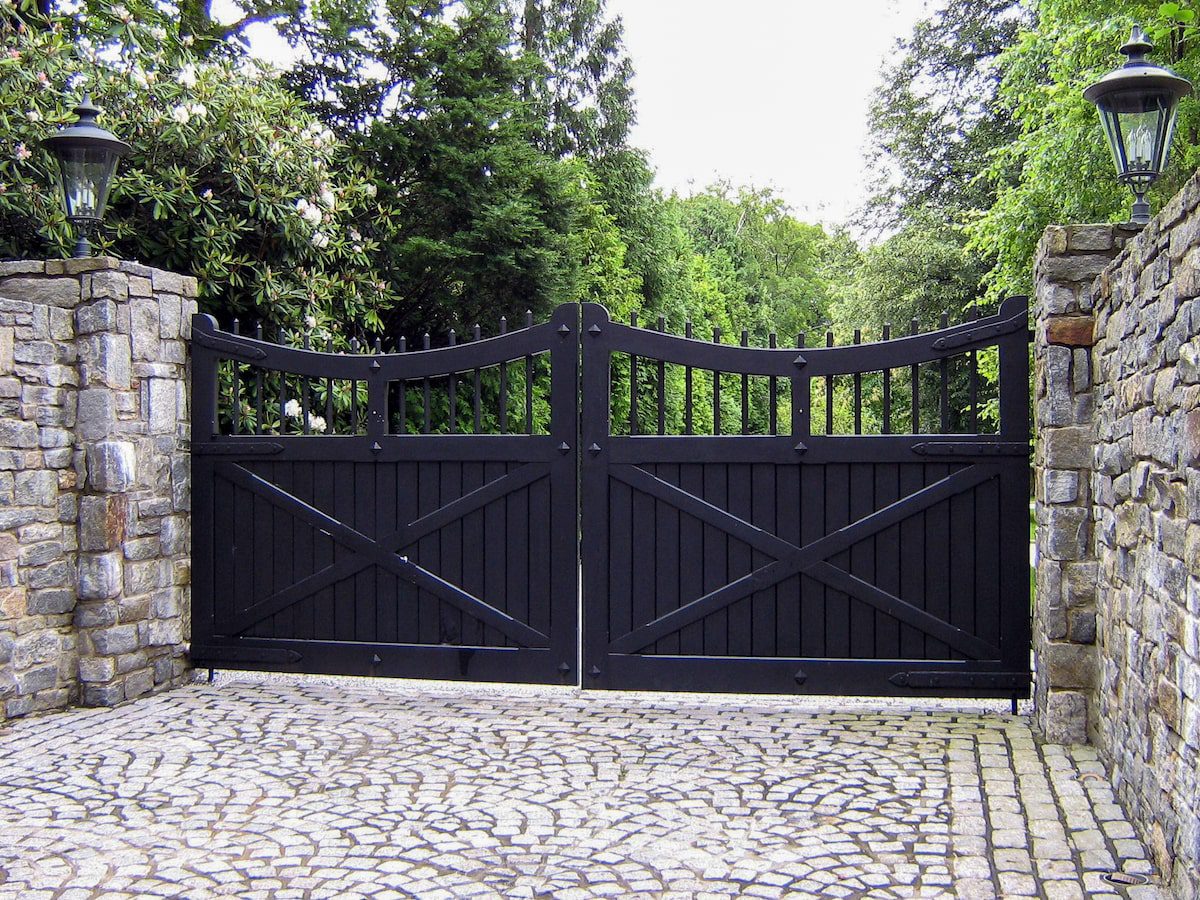 Black curved wood gate with stone columns