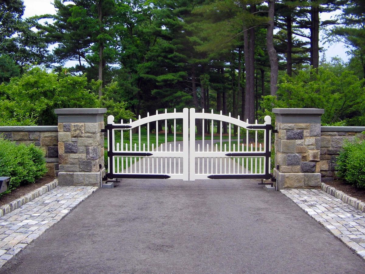 Wood and metal hardware driveway gate with stone columns